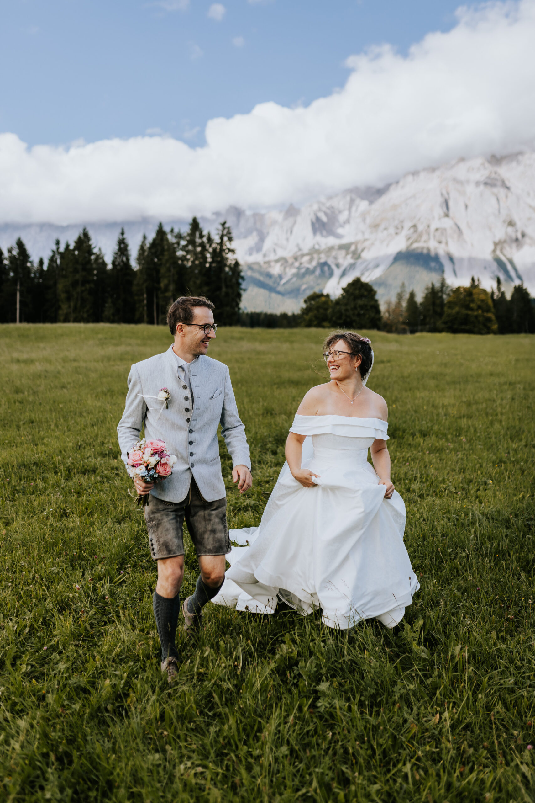 Laufendes Brautpaar in einer Wiese das sich anlächelt