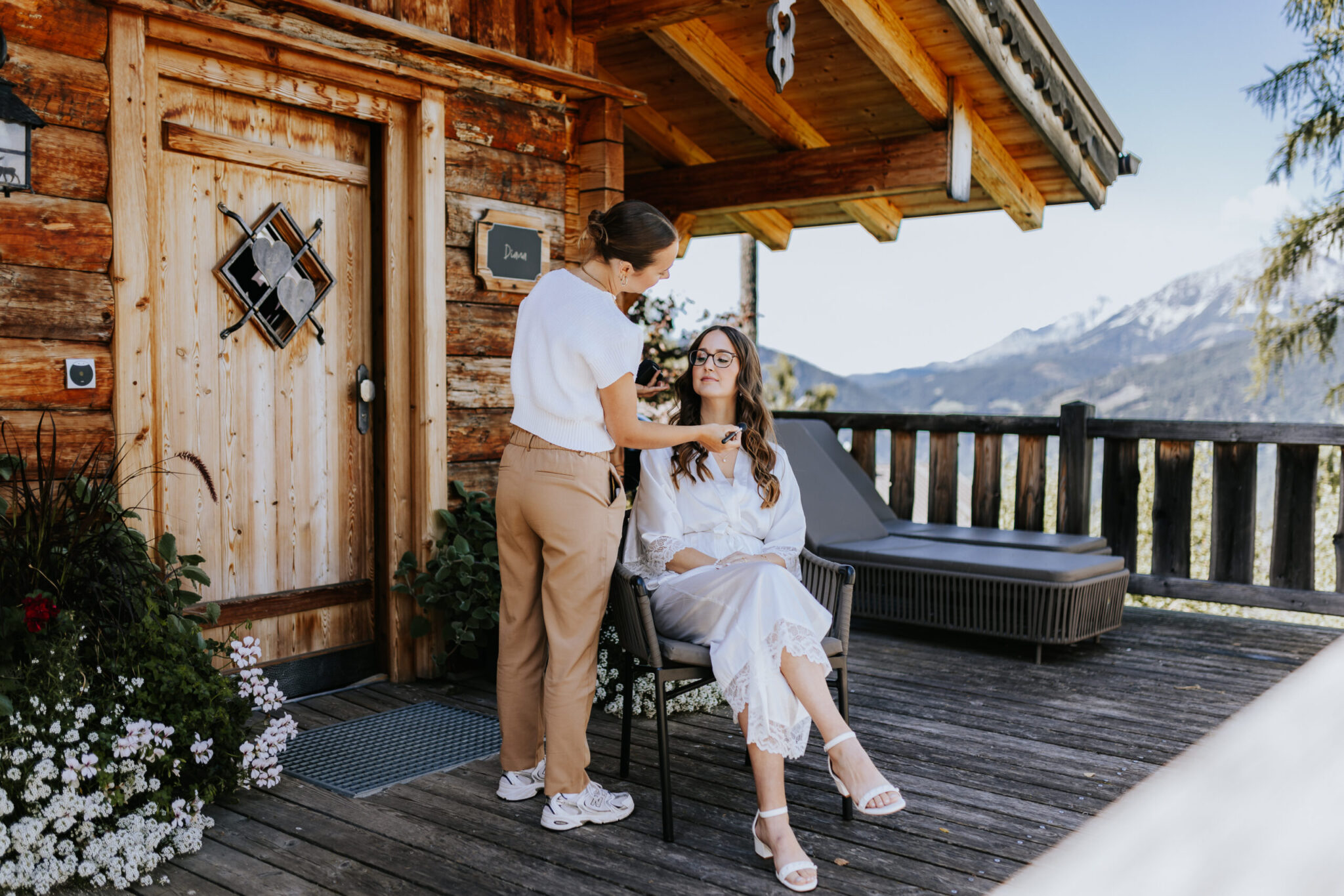 Braut im freien beim Make-Up sitzen bei einer Hütte mit den Bergen im Hintergrund